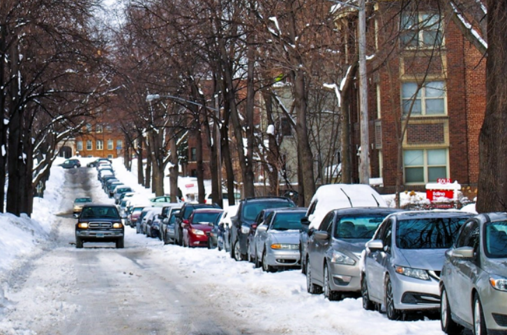 snowy Minneapolis street, with cars all parked on one side only.