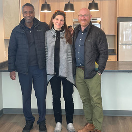 three people standing in open apartment