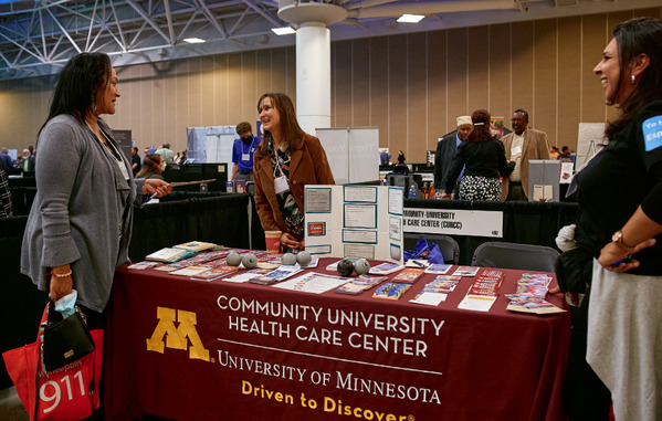 2023 Community Connections Conference exhibtor talking with attendee and volunteer