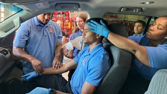 EMS Pathways Academy student interns work together to perform a mock spine stabilization after a car crash