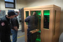 Captain Anthony Buda learns how to operate Station 11’s new infrared sauna while Firefighter Andrew Lindgren and Steve Shapira look on.