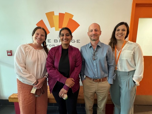 Council Vice President Aisha Chughtai and staff at the Bridge for Youth stand in front of logo for a photo.