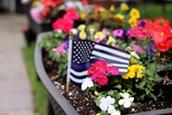 A flag with a thin blue line displays in the memorial garden for Officer Jamal Mitchell.