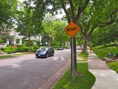 A Minneapolis street with a speed bump. A car is driving over it.