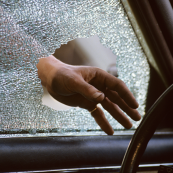 Image of a hand entering a vehicle through a shattered window