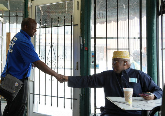 Community Safety Ambassador Willie White shakes hands with a community member at Franklin Market, a halal meats grocery store.
