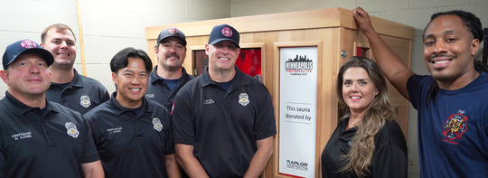 Firefighters pose in front of one of the donated saunas from the Minneapolis Fire Foundation.