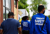 The backs of Community Safety Ambassadors walking along E. Franklin Ave.