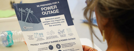 A community member reads a hand out on how to prepare for a power outage
