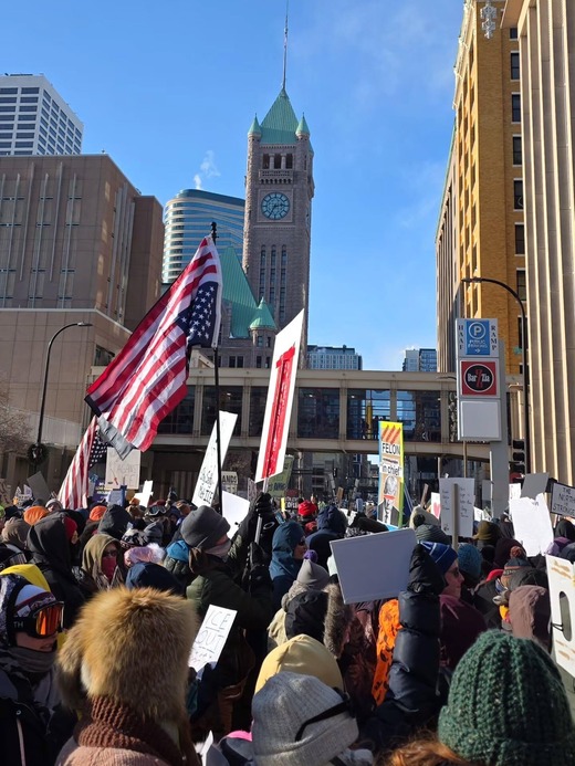 Demonstrators at the ICE Out March; holding signs and an upside down American Flag