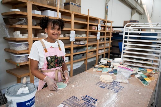 A young woman at a work station, wearing a work vest