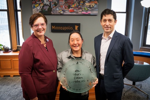 City of Minneapolis employees stand with Mayor Jacob Frey and hold a “What Works Cities Certification” glass medallion.