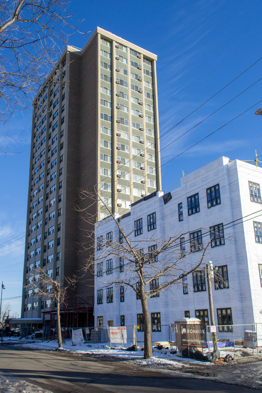 Tall building next to a four-story addition that is under construction.