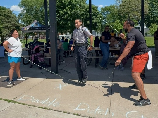 Three adults jumping double dutch at the Minneapolis Summer Safety Kickoff event