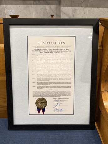 Framed honorary resolution for Annunciation Remembrance Day sitting on bench