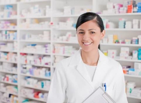 Female Pharmacist standing in front of racks of medication