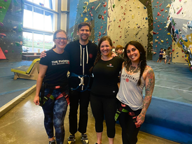 picture of four people in front of a rock climbing wall