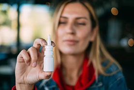 Woman holding a nasal steroid spray bottle