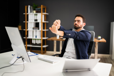 male sitting at desk stretching his wrist