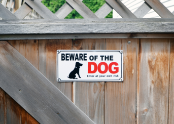 sign on wooden fence with black and red text beware of the dog, enter at your own risk