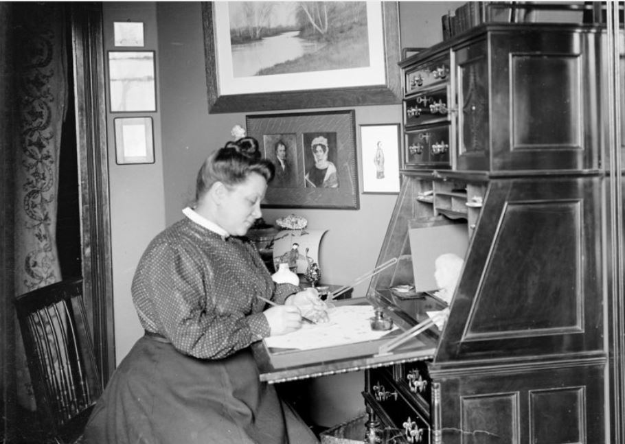 Mrs. Thompson sitting at desk, writing. 1901