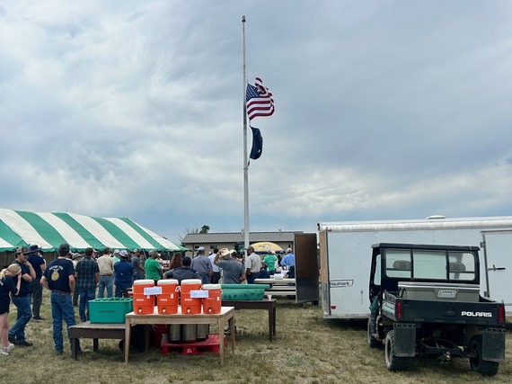People standing in line with trailer and flag pole in the foreground