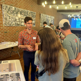 People talking in a building with maps of possible downtown streetscape on the walls