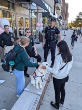 Officers talking to community members with Frankie the dog at Crumbl cookie