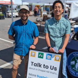 Town staff members standing in front of LUMO sign that says Come Talk To Us