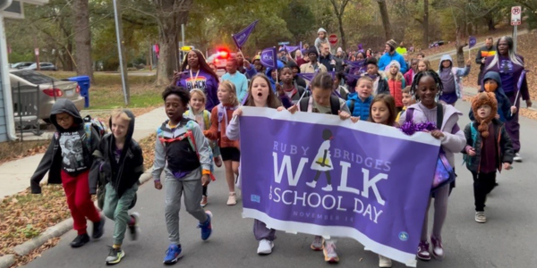 School kids holding Ruby Bridges Walk to School Day banner walking up the street
