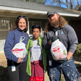 Staff members holding turkeys with Public Housing resident