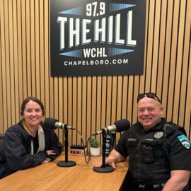 Sarah Belcher and Officer Jeffreys sitting at table with microphones at WCHL studio
