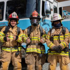 Summer Youth Employment youth in firefighter gear in front of Carolina blue fire truck