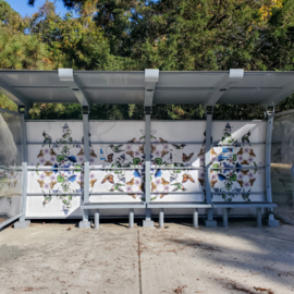 Bus shelter with hummingbirds, monarch butterflies, and flowers painted on the back window