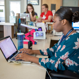 Teenager typing on a laptop sitting at a desk