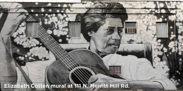 Mural of Elizabeth Cotten playing guitar painted on brick wall with windows