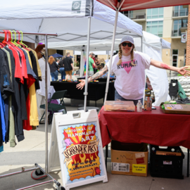 Person at a booth selling tshirts and handmade art at street festival