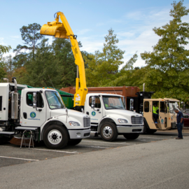 Boom truck and garbage truck in a parking lot