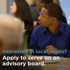 Person in blue button down collared shirt looking away from camera holding a pen