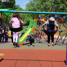 Children swinging on swings at new inclusive playground