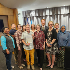 Council members at dais presenting a proclamation to recipients