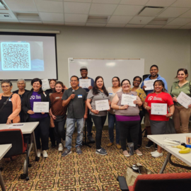 People standing at the front of a room holding certificates.
