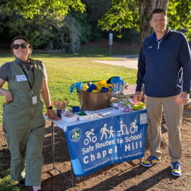 Safe routes to school coordinator and Culbreth Middle School principal at a table with giveaway items for Bike to School Day