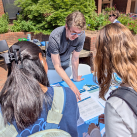 Staff member sharing information to people at an information table about coal ash at 828 MLK