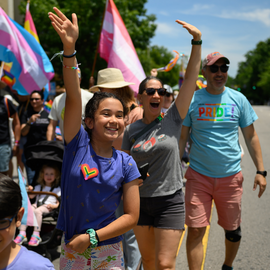 People smiling and waving during Pride promenade