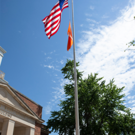 American flag on pole with orange gun violence awareness flag in front of post office at Peace & Justice plaza
