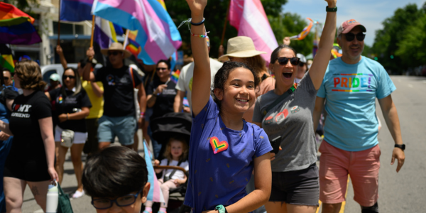 People smiling and waving in a Pride parade