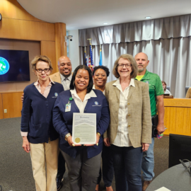 Parks and Recreation staff standing around one person holding a proclamation in the Council chamber
