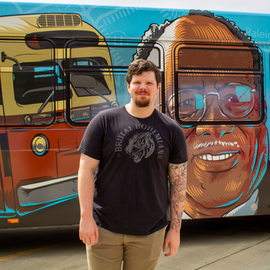 Person in black t-shirt standing in front of bus with art on it.