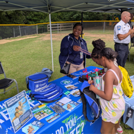 Person smiling at table with kids looking at things on table